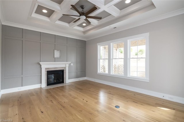 unfurnished living room featuring a fireplace with flush hearth, light wood-style flooring, ornamental molding, coffered ceiling, and a decorative wall