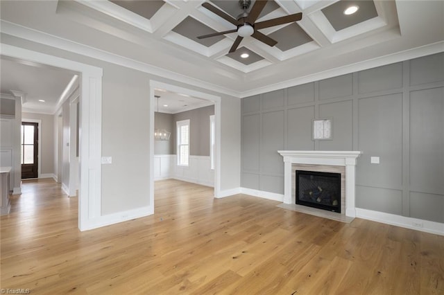 unfurnished living room featuring a decorative wall, ceiling fan with notable chandelier, coffered ceiling, and ornamental molding