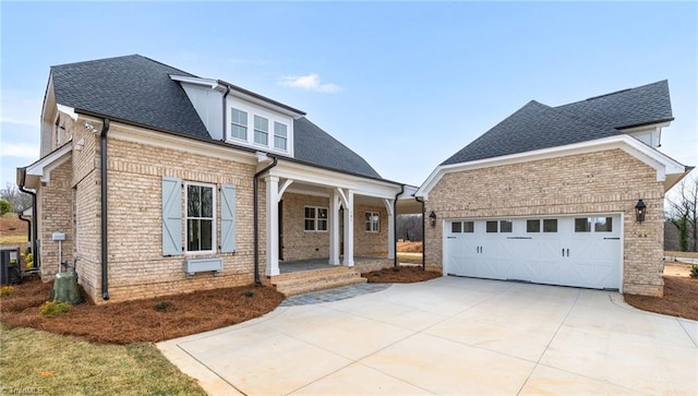 view of front of property featuring driveway, covered porch, a shingled roof, brick siding, and central AC unit