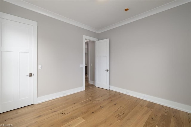 unfurnished room featuring baseboards, light wood-style flooring, and crown molding