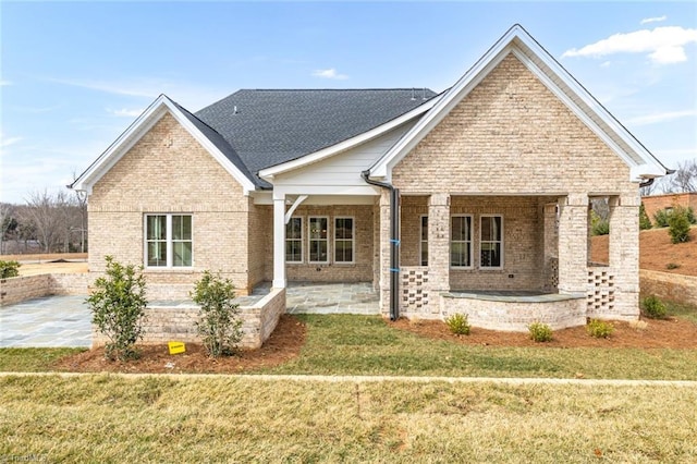 view of front of property with brick siding, a front yard, and a patio area