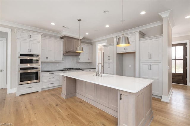 kitchen featuring light wood-type flooring, a sink, gas stovetop, double oven, and decorative backsplash