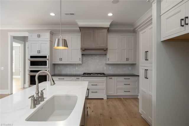 kitchen featuring stainless steel appliances, hanging light fixtures, decorative backsplash, a sink, and crown molding