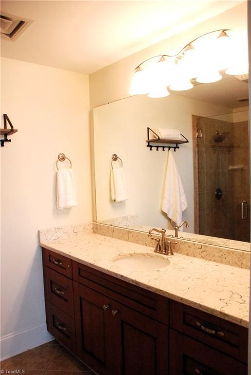 bathroom with vanity, baseboards, visible vents, tile patterned floors, and a stall shower