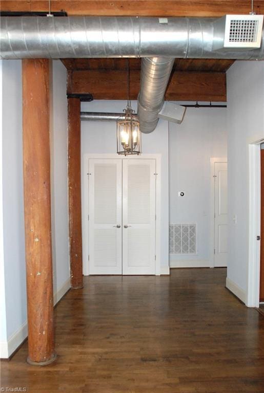 empty room with baseboards, a high ceiling, visible vents, and wood finished floors