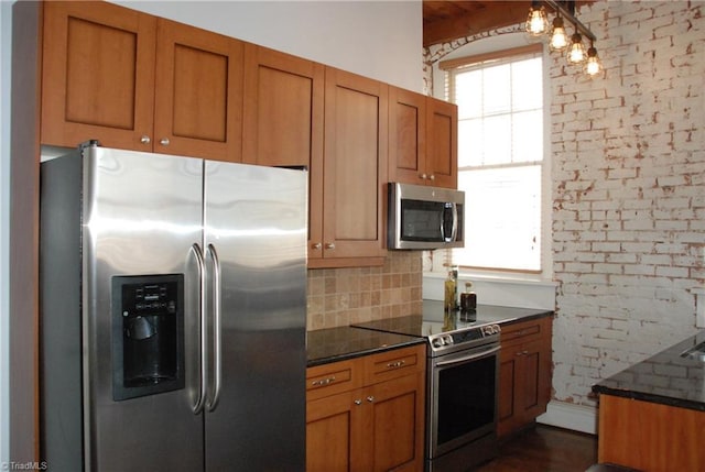 kitchen featuring stainless steel appliances, tasteful backsplash, brick wall, and brown cabinets