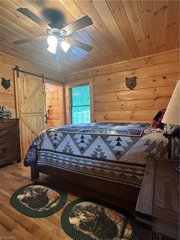 45 Wedgewood Ridge Ln, Fancy Gap, VA 24328 - bedroom with wood finished floors, wooden walls, a barn door, wooden ceiling, and a ceiling fan