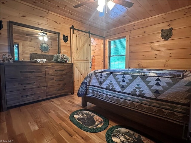 45 Wedgewood Ridge Ln, Fancy Gap, VA 24328 - bedroom with a barn door, wood walls, wood finished floors, and ceiling fan