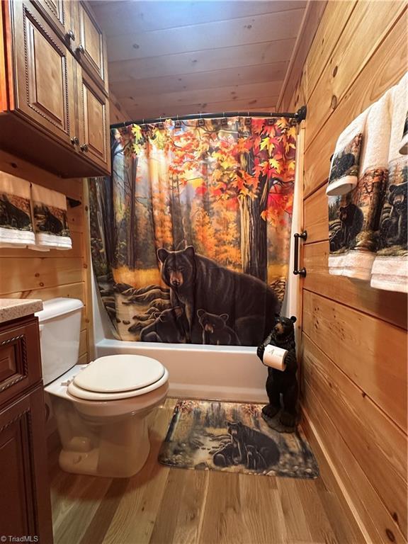 45 Wedgewood Ridge Ln, Fancy Gap, VA 24328 - bathroom featuring toilet, vanity, wood finished floors, shower / tub combo with curtain, and wood walls