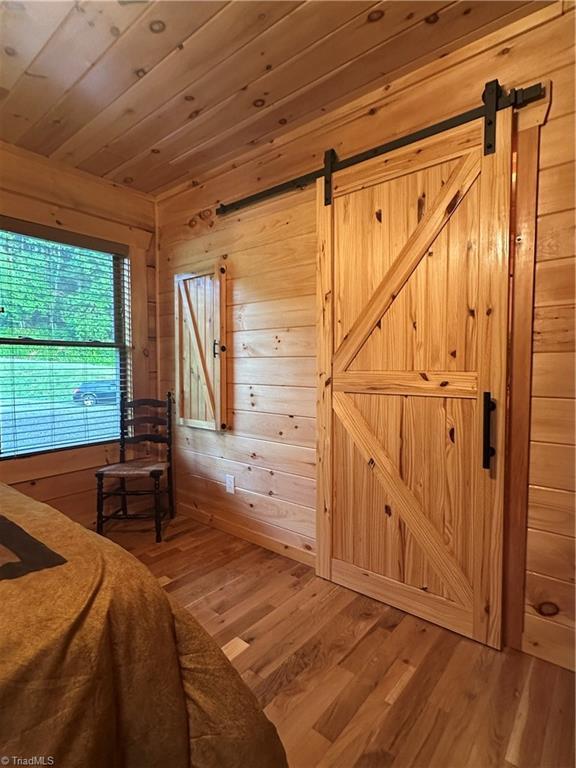 45 Wedgewood Ridge Ln, Fancy Gap, VA 24328 - bedroom featuring a barn door, wood walls, wood finished floors, and wood ceiling