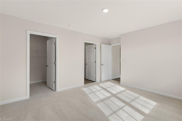 unfurnished bedroom featuring a spacious closet, light carpet, and a closet