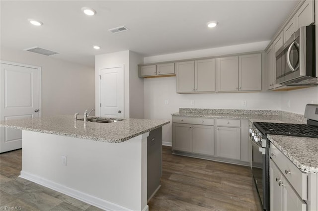 kitchen featuring dark hardwood / wood-style flooring, a center island with sink, stainless steel appliances, and sink