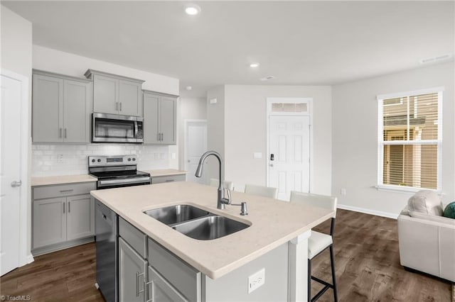 1230 Evelynnview Ln, Kernersville, NC 27284 - kitchen with gray cabinets, appliances with stainless steel finishes, a sink, a kitchen island with sink, and decorative backsplash