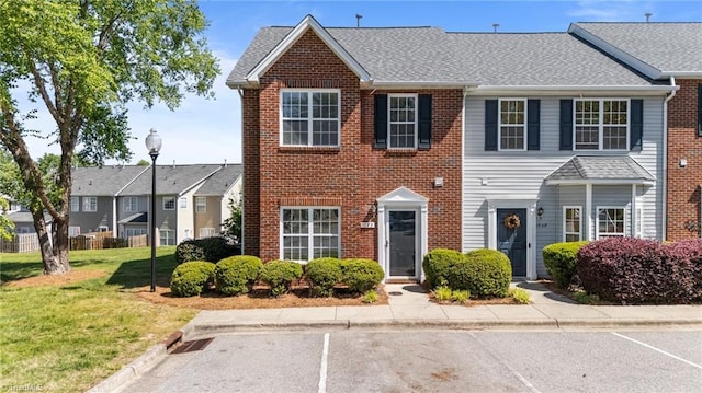 view of front of property with brick siding, uncovered parking, and a front yard