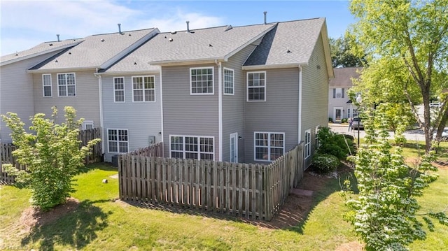 rear view of house with fence and a yard