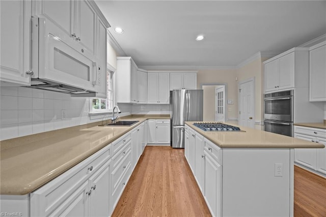 1400 Covered Wagon Rd, Mcleansville, NC 27301 - kitchen with stainless steel appliances, a sink, crown molding, light wood finished floors, and a center island