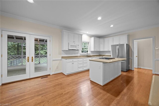 1400 Covered Wagon Rd, Mcleansville, NC 27301 - kitchen with white microwave, freestanding refrigerator, crown molding, gas cooktop, and white cabinetry