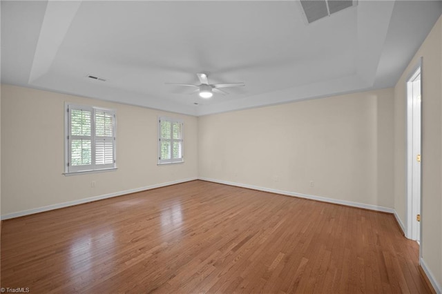 1400 Covered Wagon Rd, Mcleansville, NC 27301 - spare room with a ceiling fan, a raised ceiling, light wood-style floors, and baseboards