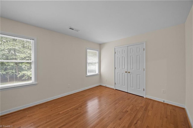 1400 Covered Wagon Rd, Mcleansville, NC 27301 - unfurnished bedroom featuring multiple windows, wood finished floors, and baseboards