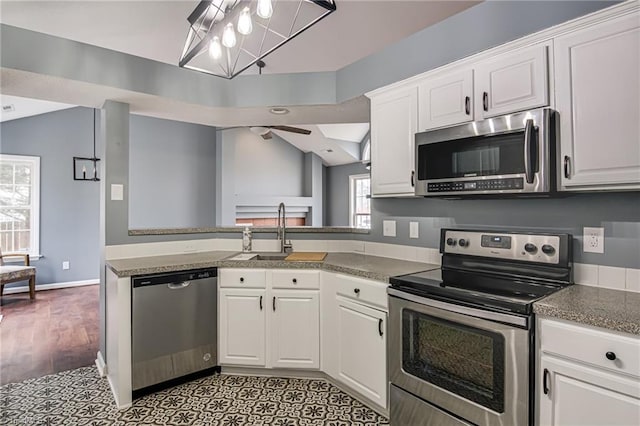 kitchen with a sink, lofted ceiling, appliances with stainless steel finishes, and white cabinets