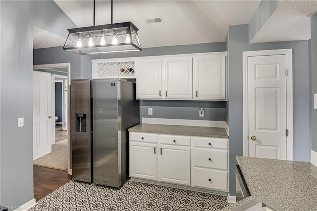 kitchen featuring visible vents, lofted ceiling, stainless steel refrigerator with ice dispenser, and white cabinetry