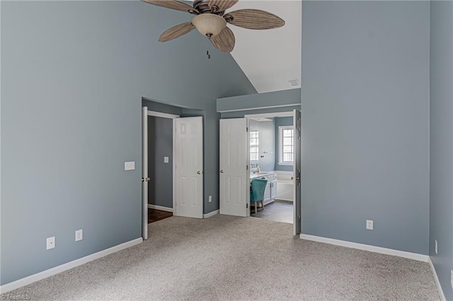 unfurnished bedroom featuring a ceiling fan, ensuite bath, carpet, baseboards, and vaulted ceiling