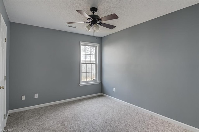 carpeted spare room featuring a textured ceiling, baseboards, visible vents, and ceiling fan