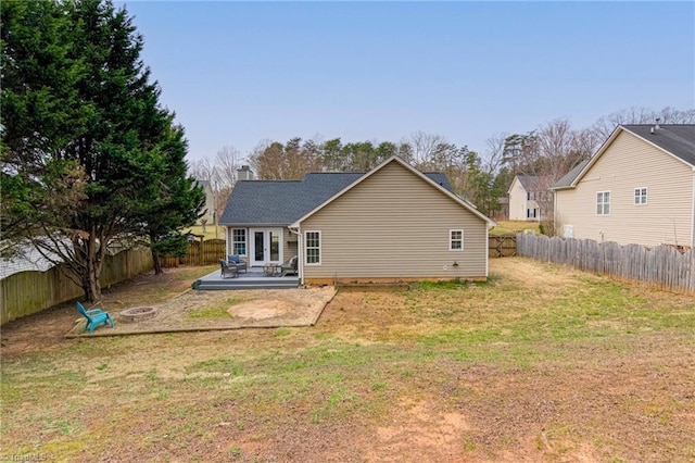 rear view of house featuring a wooden deck, a fenced backyard, a lawn, and an outdoor fire pit