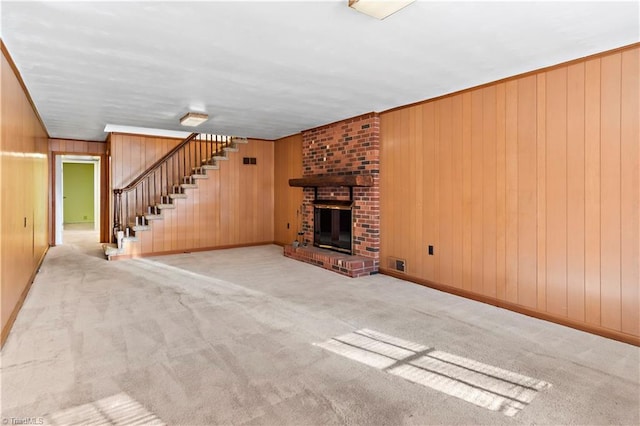 unfurnished living room with a fireplace, carpet flooring, and wood walls