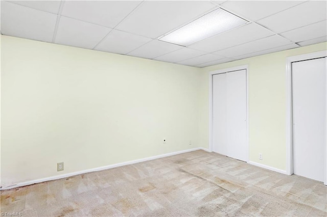 unfurnished bedroom with a paneled ceiling and light carpet