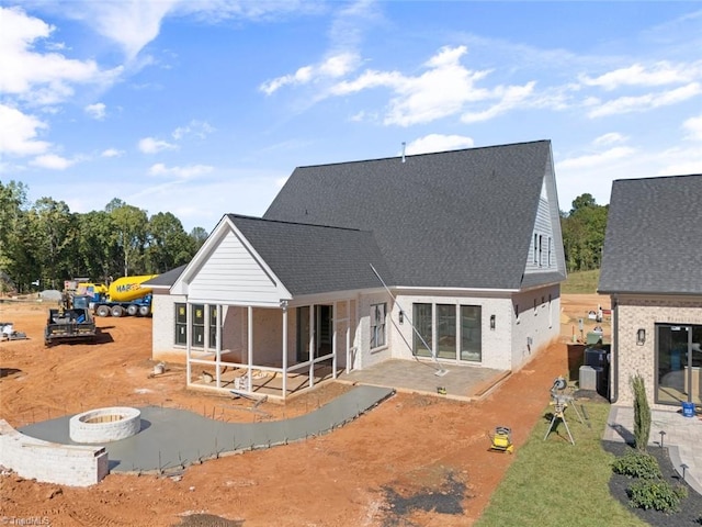 rear view of house with a patio, an outdoor fire pit, roof with shingles, and a sunroom