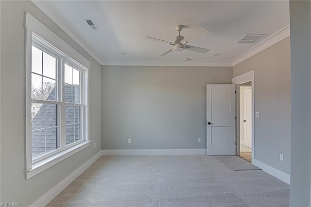 empty room with visible vents, crown molding, and baseboards