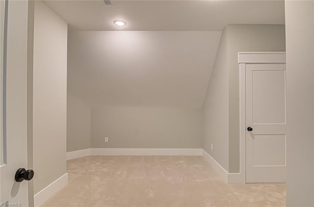 bonus room with light carpet, vaulted ceiling, and baseboards