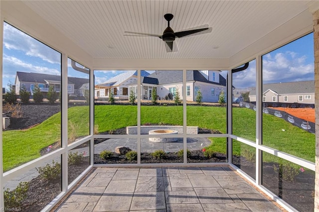 unfurnished sunroom with wood ceiling, a residential view, and a ceiling fan