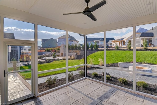 unfurnished sunroom with ceiling fan and a residential view