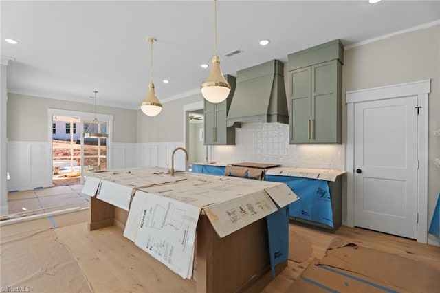 kitchen with a wainscoted wall, custom range hood, ornamental molding, and green cabinetry