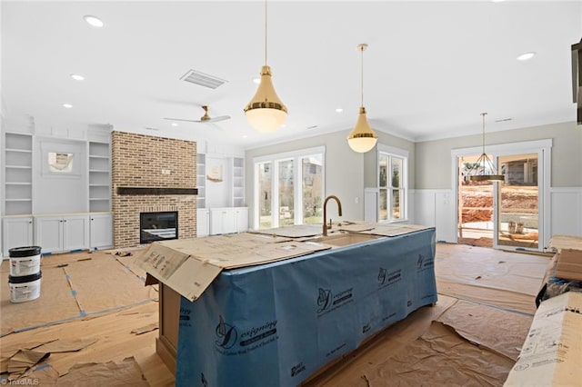 kitchen featuring visible vents, built in features, a wainscoted wall, ornamental molding, and recessed lighting