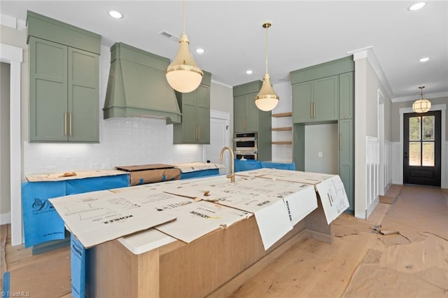 kitchen featuring visible vents, green cabinetry, custom exhaust hood, crown molding, and a sink