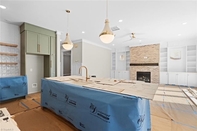 kitchen featuring visible vents, hanging light fixtures, light countertops, a brick fireplace, and built in shelves