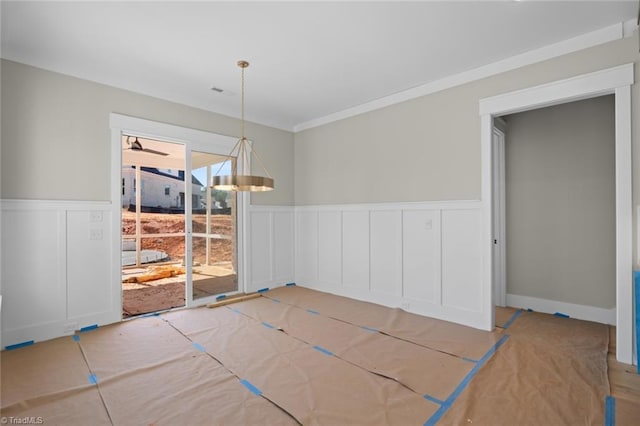 unfurnished dining area featuring wainscoting and crown molding