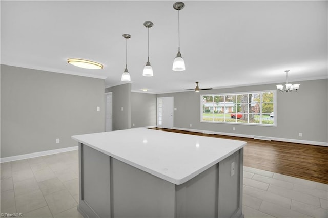 kitchen with decorative light fixtures, ornamental molding, ceiling fan, and a kitchen island