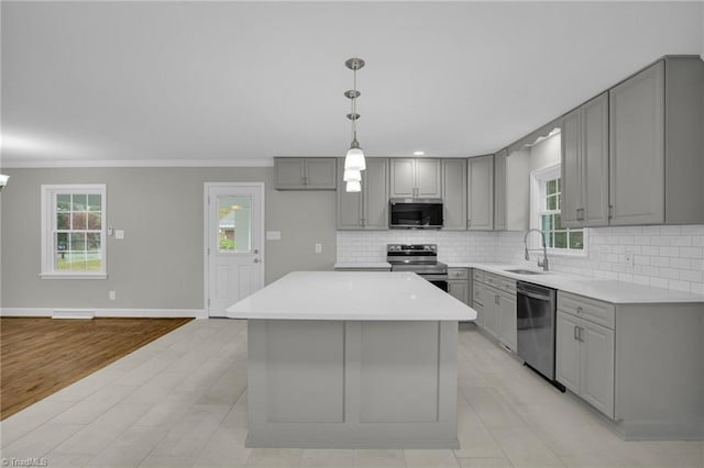 kitchen with sink, appliances with stainless steel finishes, gray cabinetry, a center island, and tasteful backsplash