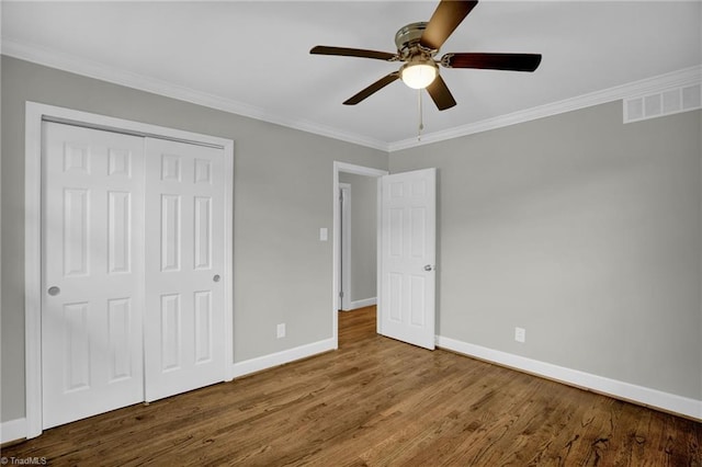 unfurnished bedroom with ornamental molding, hardwood / wood-style floors, ceiling fan, and a closet