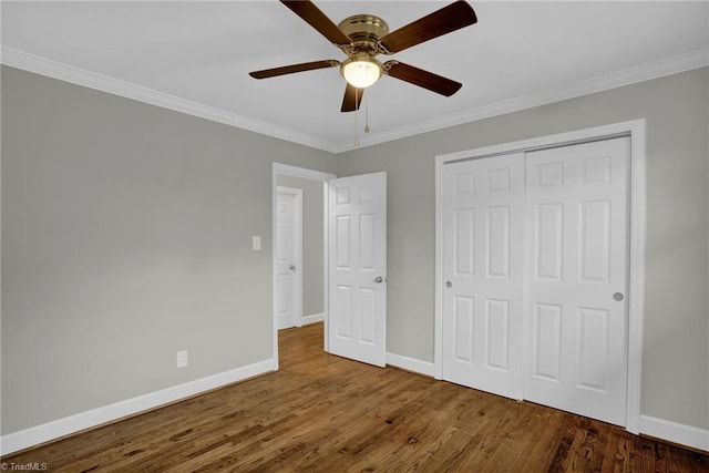 unfurnished bedroom with a closet, ornamental molding, dark hardwood / wood-style floors, and ceiling fan