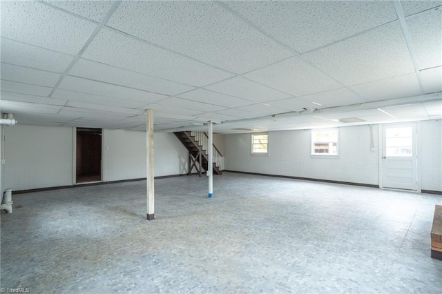 basement with brick wall and a paneled ceiling