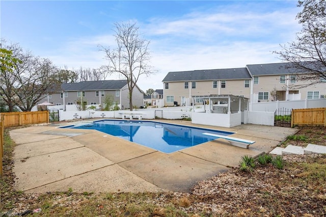 view of pool with a diving board and a patio