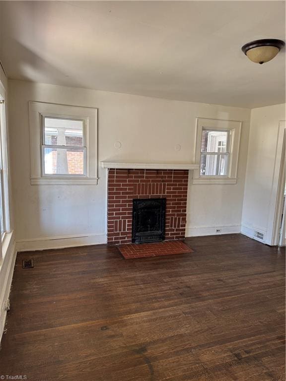 unfurnished living room featuring a fireplace, dark wood finished floors, visible vents, and baseboards