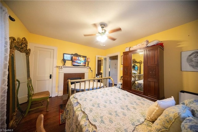 bedroom with ceiling fan, dark hardwood / wood-style floors, and a fireplace