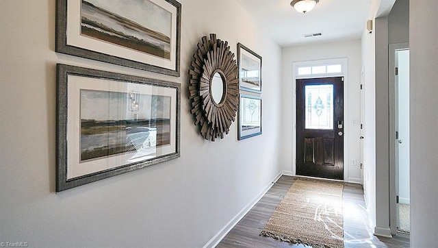 foyer with dark wood-style floors, visible vents, and baseboards