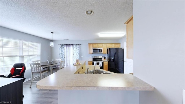 kitchen with light brown cabinetry, decorative light fixtures, sink, kitchen peninsula, and stainless steel appliances